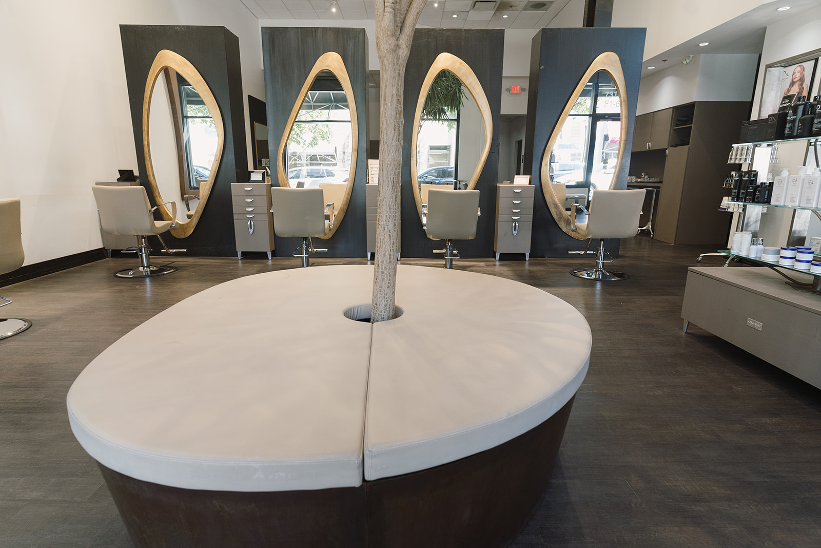 Styling stations with gold mirrors and a circular waiting bench around a tree